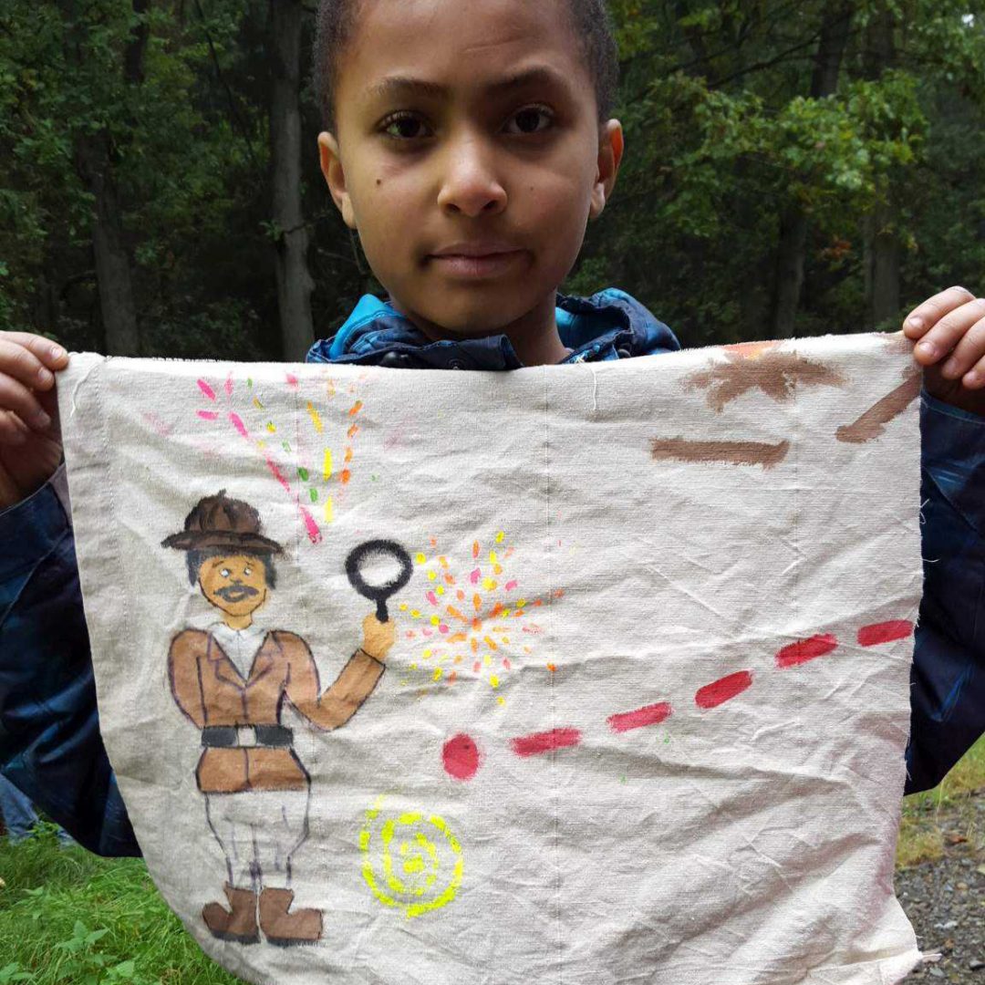 Porträt eines Jungen auf der inklusiven Herbstreise des Indiwi Berlins. Er hält ein bemaltes Tuch in seinen Händen.